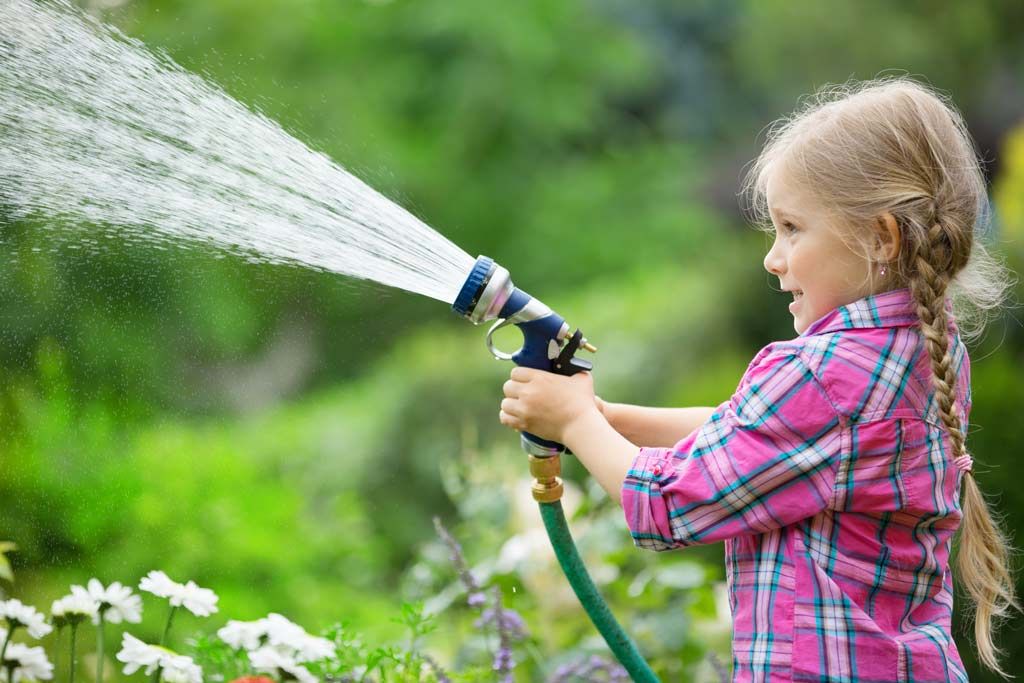 Kleines Mädchen gießt den Garten